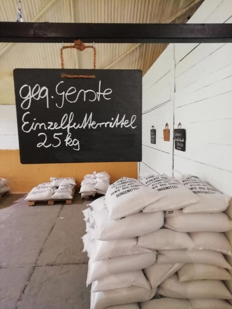 Ein Stapel weißer Säcke mit schwarzer Aufschrift steht unter einem großen Preisschild