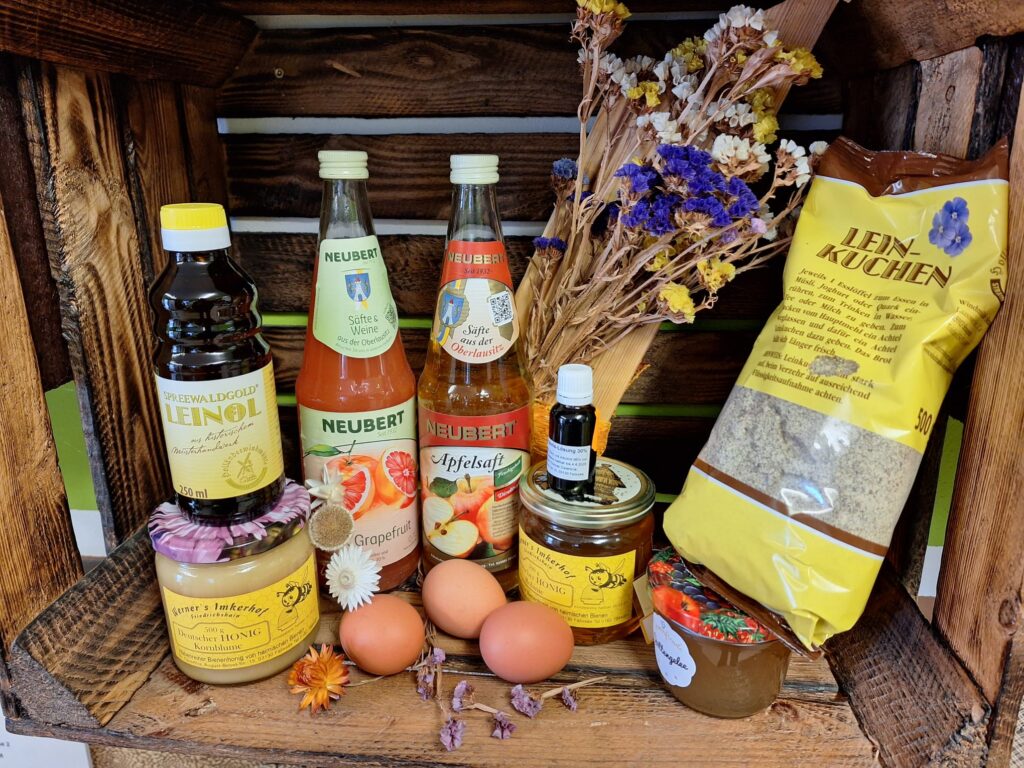 Verschiedene regionale Produkte wie Saft, Eier, Öl, Honig und Blüten in einer Holzkiste